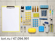 Клипборд и медицинские принадлежности с инсулиновым шприцем, таблетками и инфракрасным термометром на белой плиточной поверхности. Вид сверху. Стоковое фото, фотограф Pixel_shot / Фотобанк Лори