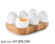 Деревянная подставка с треснутыми и целыми куриными яйцами на белом фоне. Стоковое фото, фотограф Pixel_shot / Фотобанк Лори