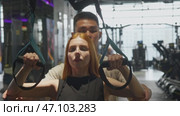 Korean fitness trainer helps a girl do pull-up by supporting her with her elbows and helping her distribute weight evenly. Portrait. Стоковое видео, видеограф Strunov David / Фотобанк Лори