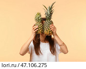 Молодая женщина скрывается лицо за двумя ананасами на цветном фоне. Стоковое фото, фотограф Pixel_shot / Фотобанк Лори