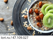 Чаша с вкусной овсянкой, нарезанным киви и орехами на деревянном столе. Стоковое фото, фотограф Pixel_shot / Фотобанк Лори