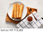 Тарелка с вкусными вафельными трубочками и миска вареного сгущенного молока на белом гранж-фоне. Стоковое фото, фотограф Pixel_shot / Фотобанк Лори