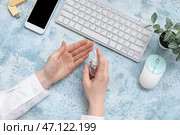 Женщина наносит антисептик на руки за синим столом в офисе. Стоковое фото, фотограф Pixel_shot / Фотобанк Лори