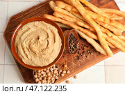Чаша с вкусным хумусом и итальянским гриссини на фоне белой плитки. Стоковое фото, фотограф Pixel_shot / Фотобанк Лори