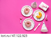 Бумажные одноразовые тарелки с пончиками, гудками и шляпами на розовом фоне. Стоковое фото, фотограф Pixel_shot / Фотобанк Лори