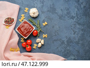 Композиция с миской вкусной томатной пасты, сырой пастой фарфалле и розмарином на синем гранж-фоне. Стоковое фото, фотограф Pixel_shot / Фотобанк Лори