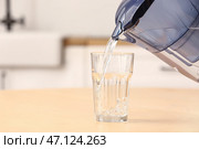 Налить чистую воду из фильтрующего кувшина в стакан на столе на кухне. Стоковое фото, фотограф Pixel_shot / Фотобанк Лори