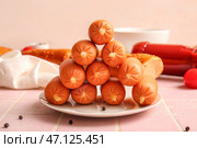 Тарелка вкусных отварных колбасок и багета на розовом фоне плитки. Стоковое фото, фотограф Pixel_shot / Фотобанк Лори