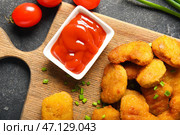 Доска с вкусными наггетсами, кетчупом и помидорами на черном столе. Стоковое фото, фотограф Pixel_shot / Фотобанк Лори