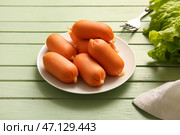 Тарелка вкусных отварных колбасок и салата на зеленом деревянном фоне. Стоковое фото, фотограф Pixel_shot / Фотобанк Лори