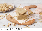 Доска с вкусной халвой и арахисом на белом фоне. Стоковое фото, фотограф Pixel_shot / Фотобанк Лори