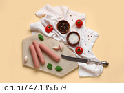 Доска вкусных колбасок с базиликом и помидорами на бежевом фоне. Стоковое фото, фотограф Pixel_shot / Фотобанк Лори