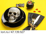 Сервировка стола с черепом и декором Хэллоуина на желтом фоне, крупным планом. Стоковое фото, фотограф Pixel_shot / Фотобанк Лори