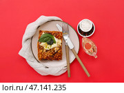 Тарелка вкусного итальянского пирога с моцареллой, соусом песто, специями и маслом на красном фоне. Стоковое фото, фотограф Pixel_shot / Фотобанк Лори