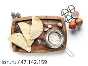 Доска с сырыми чебуреками, специями, ситом, мукой и яйцами на белом фоне. Стоковое фото, фотограф Pixel_shot / Фотобанк Лори