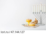 Менора со свечами, печеньем, пончиками и дрейделами на светлом фоне. Стоковое фото, фотограф Pixel_shot / Фотобанк Лори