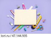 Чистый лист бумаги с универсальными ножами и канцелярскими принадлежностями на фиолетовом фоне. Стоковое фото, фотограф Pixel_shot / Фотобанк Лори