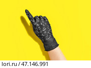 Рука в черной медицинской перчатке с рисунками улыбки, указывающей на что-то на цветном фоне. Стоковое фото, фотограф Pixel_shot / Фотобанк Лори