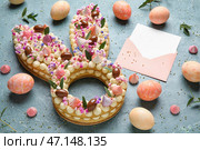 Композиция с красивым тортом, крашеными яйцами и конвертом для празднования Пасхи на цветном фоне. Стоковое фото, фотограф Pixel_shot / Фотобанк Лори