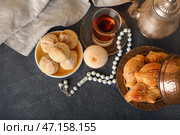 Вкусные восточные сладости и чай с тасбихом на темном фоне. Стоковое фото, фотограф Pixel_shot / Фотобанк Лори