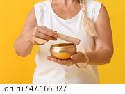Зрелая женщина с тибетской поющей чашей на цветном фоне. Стоковое фото, фотограф Pixel_shot / Фотобанк Лори