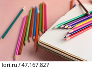 Блокнот с разноцветными карандашами на розовом столе, крупным планом. Стоковое фото, фотограф Pixel_shot / Фотобанк Лори