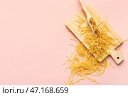 Деревянная доска с макаронами из сырой вермишели на розовом фоне. Стоковое фото, фотограф Pixel_shot / Фотобанк Лори
