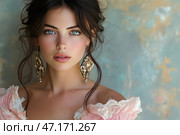 A young woman with captivating blue eyes and delicate features. She has dark wavy hair, casually gathered into a romantic hairstyle, with a few loose strands framing her face. She is dressed in a delicate pink dress with lace, creating a vintage or bohemian feel. Large gold earrings with a patterned design add nobility and sophistication to the image. The background of an aged bluish wall emphasizes the contrast between the girl's natural beauty and the textured surface, creating the effect of an artistic portrait. Стоковое AI-изображение, AI-художник Анна Кривицкая / Фотобанк Лори