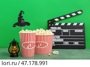Ведра с вкусным попкорном, фонарь и клипборд на зеленом фоне. Празднование Хэллоуина. Стоковое фото, фотограф Pixel_shot / Фотобанк Лори