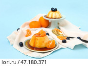 Вкусные пудинги, мандарины и черника в карамельном сиропе на синем фоне. Стоковое фото, фотограф Pixel_shot / Фотобанк Лори