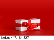 Подарочная коробка с красивым бантом на красном фоне. Празднование Дня святого Валентина. Стоковое фото, фотограф Pixel_shot / Фотобанк Лори