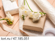 Композиция с подарочными коробками, оберточной бумагой и красивыми цветами фрезии на цветном деревянном фоне, крупным планом. Празднование женского дня. Стоковое фото, фотограф Pixel_shot / Фотобанк Лори