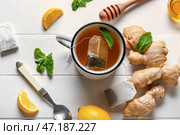 Чашка чая с мятой, имбирем, ложкой и лимоном на деревянном фоне. Стоковое фото, фотограф Pixel_shot / Фотобанк Лори