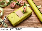 Композиция с подарочной коробкой, оберточной бумагой, лентой и цветами альстромерии на деревянном фоне, крупным планом. Празднование женского дня. Стоковое фото, фотограф Pixel_shot / Фотобанк Лори