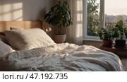 The interior of a modern house. A minimalistic cozy beige bedroom interior with a plaid, pillows, a headboard, linen linens and a bedside table. Стоковое AI-изображение, AI-художник Photojuli / Фотобанк Лори