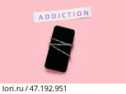 Мобильный телефон с цепочкой и словом ЗАВИСИМОСТЬ на цветном фоне. Стоковое фото, фотограф Pixel_shot / Фотобанк Лори