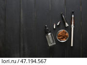 Электронная сигарета с маслом и табаком на фоне темного дерева. Стоковое фото, фотограф Pixel_shot / Фотобанк Лори