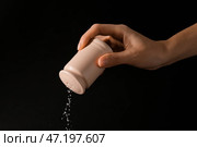 Женщина сыпет соль из шейкера на темном фоне, крупным планом. Стоковое фото, фотограф Pixel_shot / Фотобанк Лори