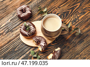 Чашка свежесваренного кофе и пончики на деревянном столе. Стоковое фото, фотограф Pixel_shot / Фотобанк Лори