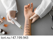 Врач со шприцем и отмеченной рукой пациента для кожных тестов на аллергию на сером фоне. Стоковое фото, фотограф Pixel_shot / Фотобанк Лори