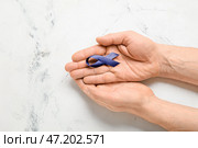 Мужские руки с голубой лентой на светлом фоне. Концепция рака толстой кишки. Стоковое фото, фотограф Pixel_shot / Фотобанк Лори