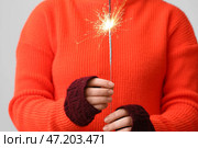 Женщина в красном свитере с рождественским бенгальским огнем на сером фоне, крупным планом. Стоковое фото, фотограф Pixel_shot / Фотобанк Лори