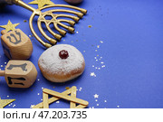 Менора с пончиками и дрейделами для празднования Хануки на синем фоне крупным планом. Стоковое фото, фотограф Pixel_shot / Фотобанк Лори