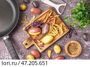 Деревянная доска с нарезанным и целым сырым картофелем, сковородкой, овощечисткой и зеленью на фоне гранж. Стоковое фото, фотограф Pixel_shot / Фотобанк Лори