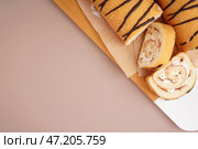 Деревянная доска с вкусными бисквитными рулетиками на цветном фоне. Стоковое фото, фотограф Pixel_shot / Фотобанк Лори