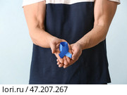 Человек с голубой лентой на цветном фоне, крупным планом. Концепция рака толстой кишки. Стоковое фото, фотограф Pixel_shot / Фотобанк Лори