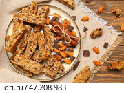 Тарелка с вкусным печеньем бискотти, миндальными орехами, корицей, шоколадом и салфеткой на деревянном фоне. Стоковое фото, фотограф Pixel_shot / Фотобанк Лори