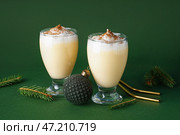 Стакан вкусного коктейля из гоголя-моголь, елочный шар и еловые ветки на зеленом фоне. Стоковое фото, фотограф Pixel_shot / Фотобанк Лори