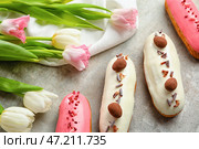 Вкусные глазированные эклеры и тюльпаны на сером столе. Стоковое фото, фотограф Pixel_shot / Фотобанк Лори