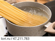 Кастрюля с сырыми макаронами и кипящей водой на электрической плите на кухне. Стоковое фото, фотограф Pixel_shot / Фотобанк Лори